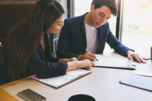 Businessman and businesswoman signing paper (insurance contract important)