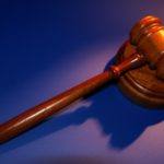 Wooden judges gavel on a blue purple background on personal injury law website.