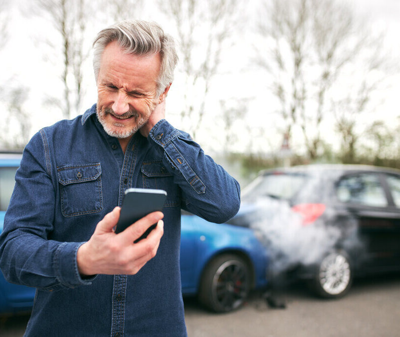 Injured man looking at phone after a car accident