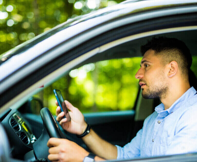 Man driving a car with the phone in his hand
